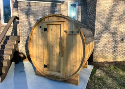 Outdoor cedar sauna with electric heater built by Sauna Craft, front door beside a brick house