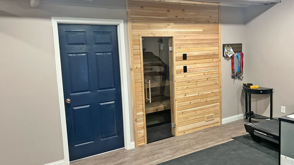 Basement sauna with a glass door set into a cedar wall, built by Sauna Craft