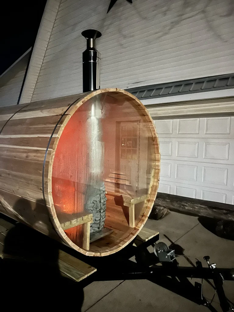 Custom trailer sauna at night, with a warm glow through the glass end wall